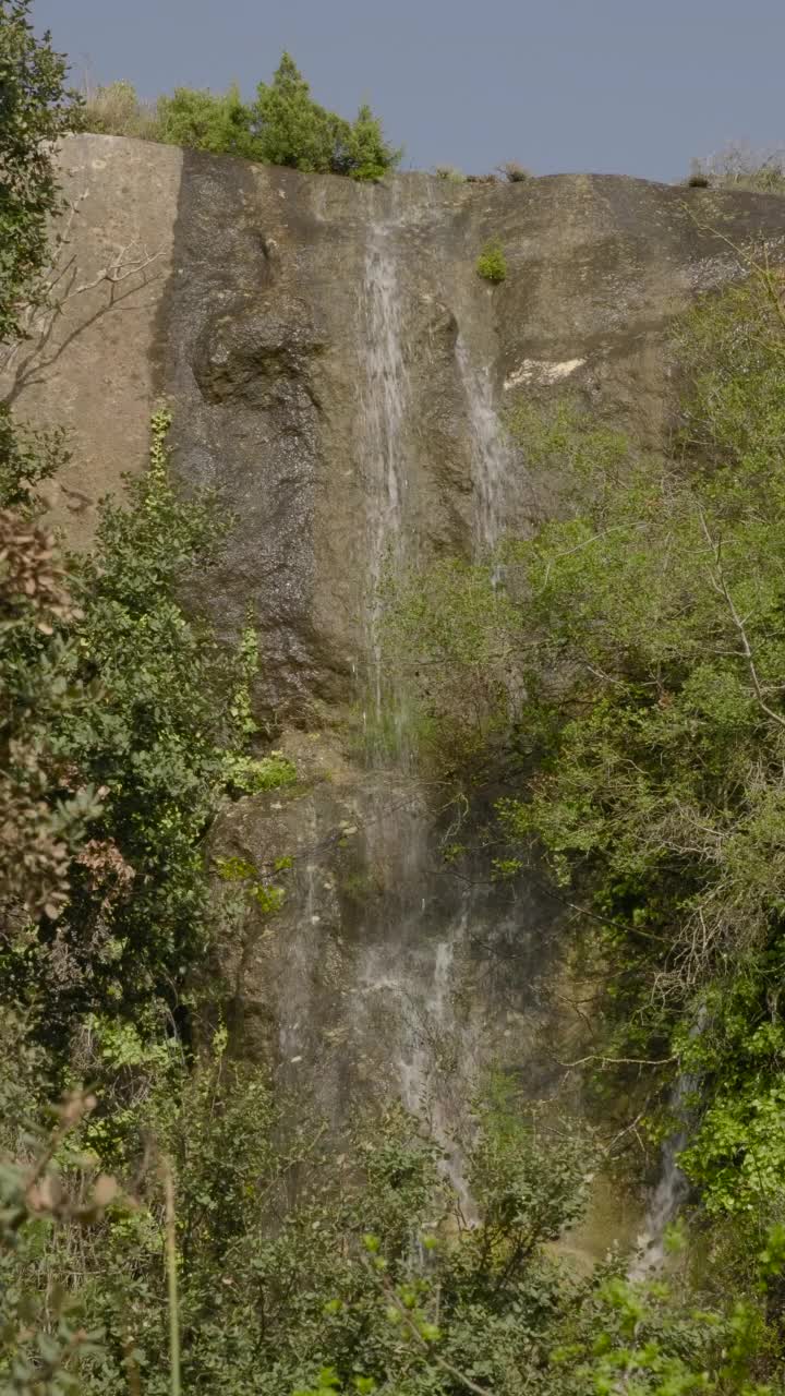 山景，瀑布从森林的岩石间倾泻而下。视频素材