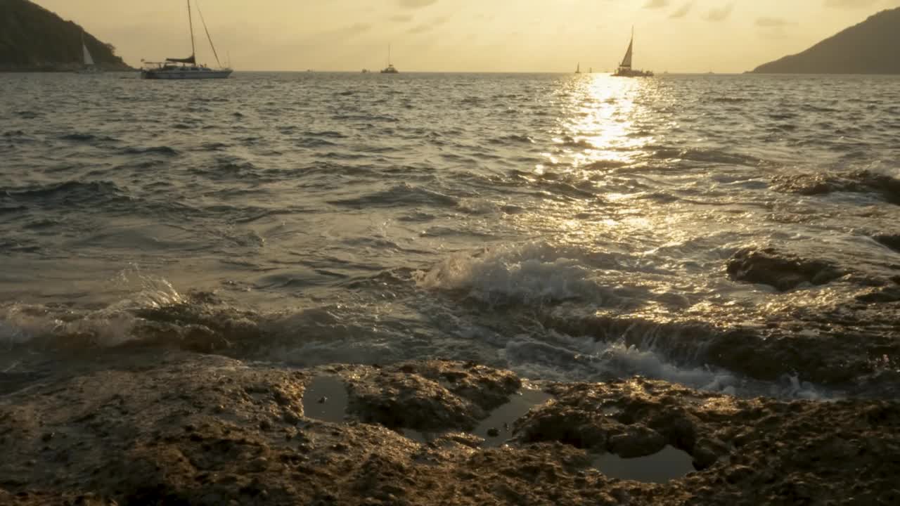 慢动作4k，许多游客乘几艘船在涨潮和巨浪期间观看日落。海浪拍打着岩石。视频素材