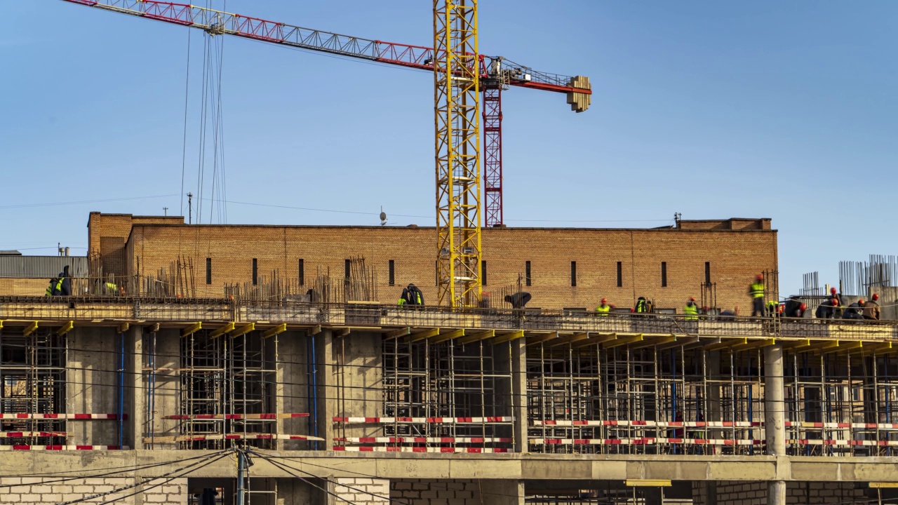 起重机和建筑工人在河堤上建设大学办公楼和学术大楼期间，精力充沛的工作，时间流逝视频下载