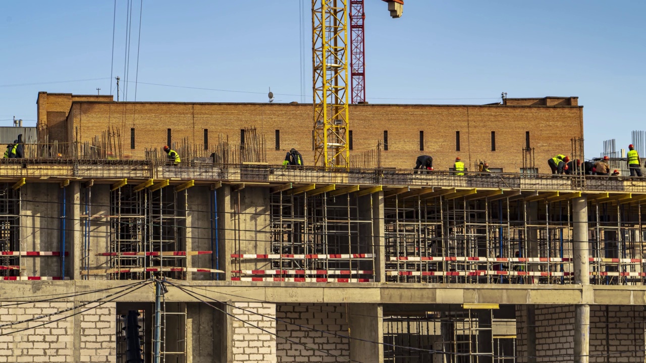 起重机和建筑工人在河堤上建设大学办公楼和学术大楼期间，精力充沛的工作，时间流逝视频下载