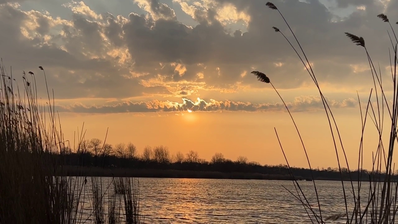 金色的夕阳映在湖面上。浪漫的橙色的《暮光之城》。明亮的夜空。视频素材