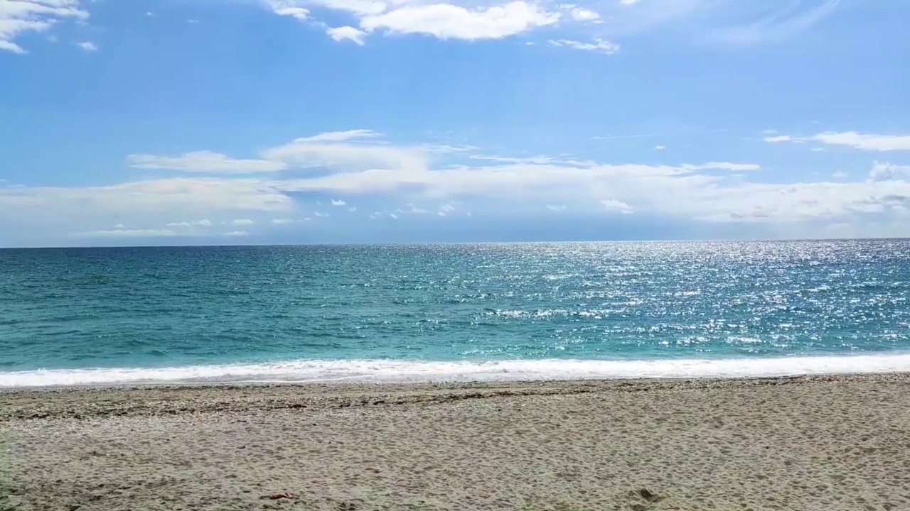 海浪拍打着海岸上的石头。蓝色的大海，淡淡的暴风雨，白色的浪花，晴朗的天气。视频下载