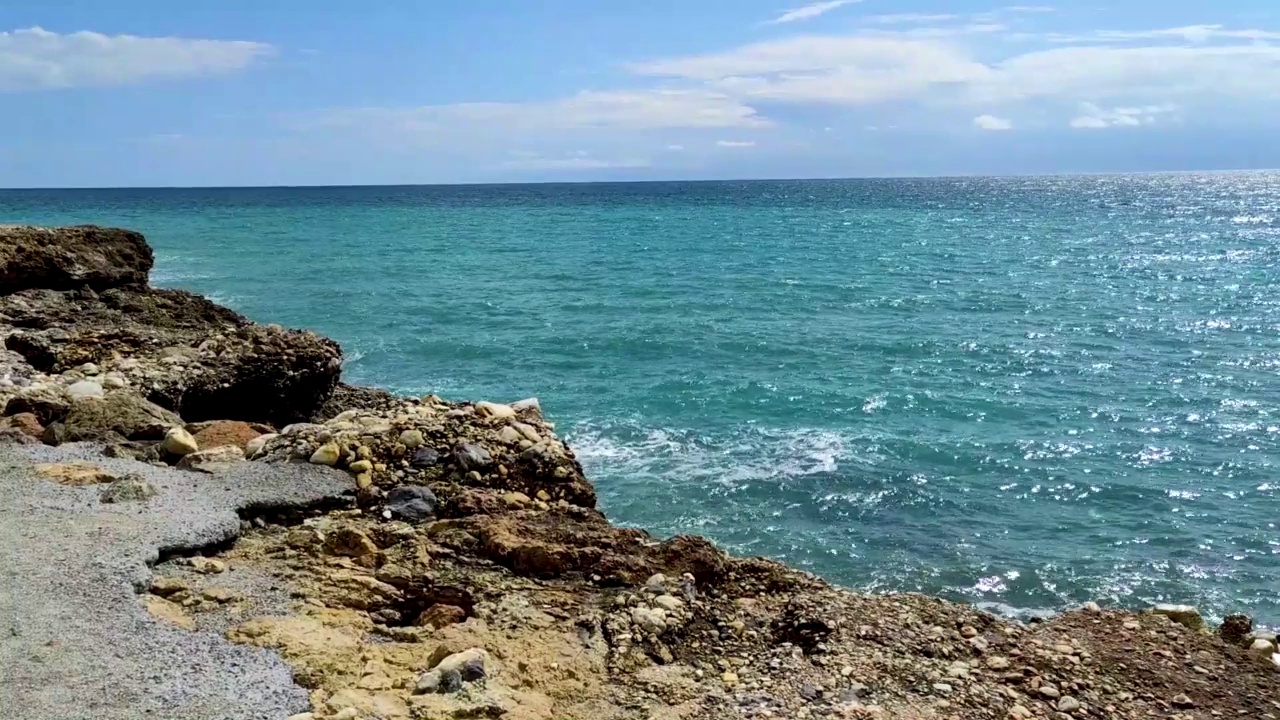 海浪拍打着海岸上的石头。蓝色的大海，淡淡的暴风雨，白色的浪花，晴朗的天气。视频素材