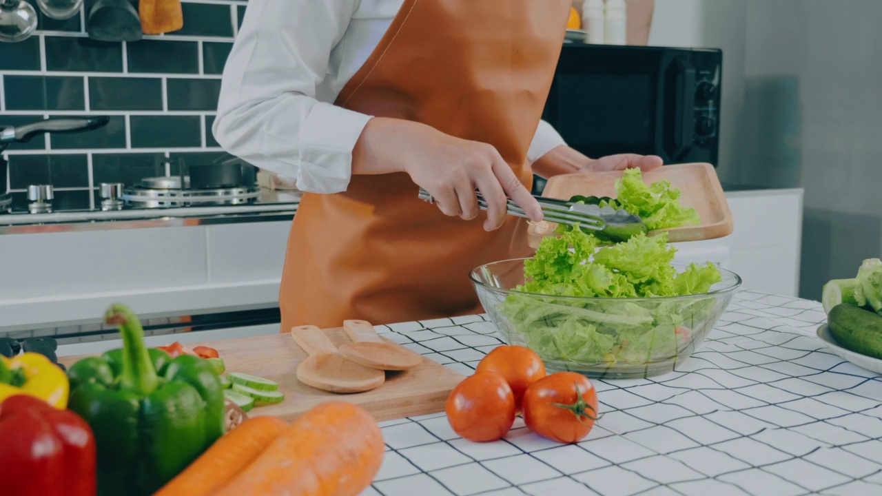 一名素食妇女在厨房做饭时用碗搅拌蔬菜沙拉视频素材