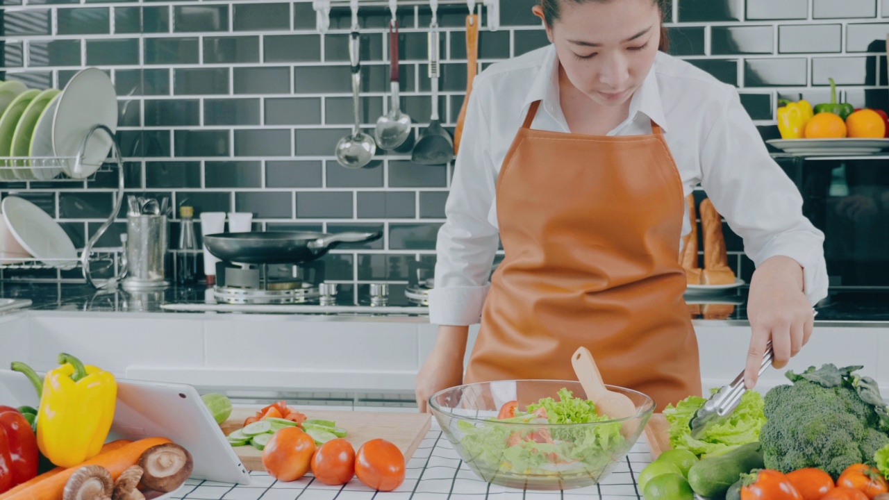 一名素食妇女在厨房做饭时用碗搅拌蔬菜沙拉视频素材