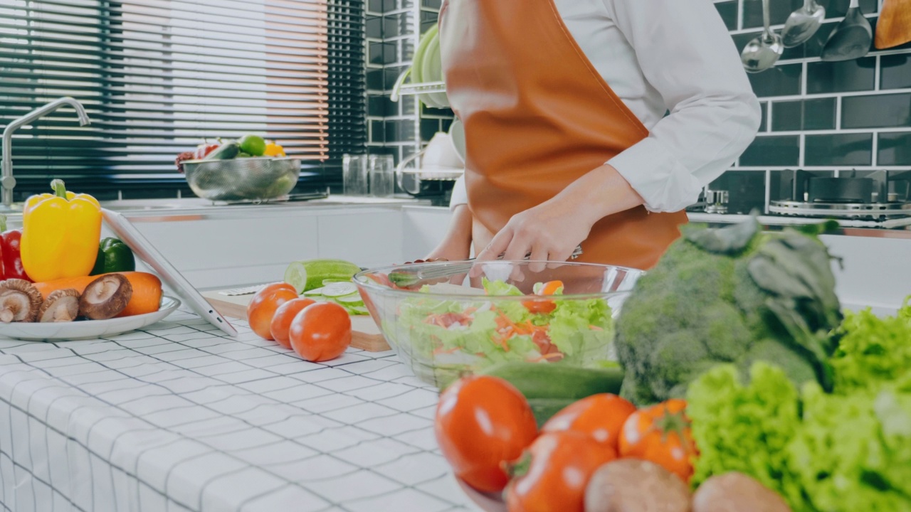 一名素食妇女在厨房做饭时用碗搅拌蔬菜沙拉视频素材