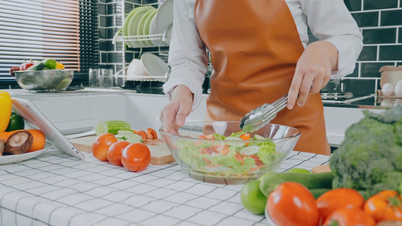 一名素食妇女在厨房做饭时用碗搅拌蔬菜沙拉视频素材