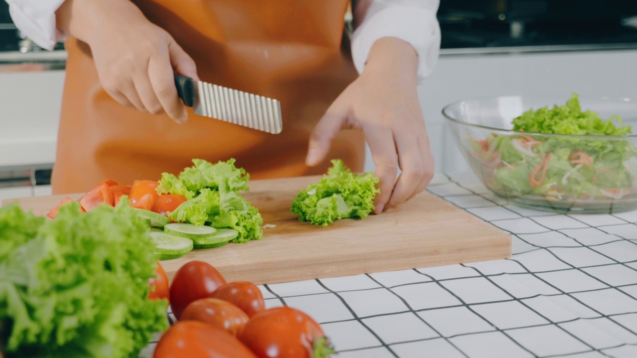 一名素食妇女在厨房做饭时用碗搅拌蔬菜沙拉视频素材