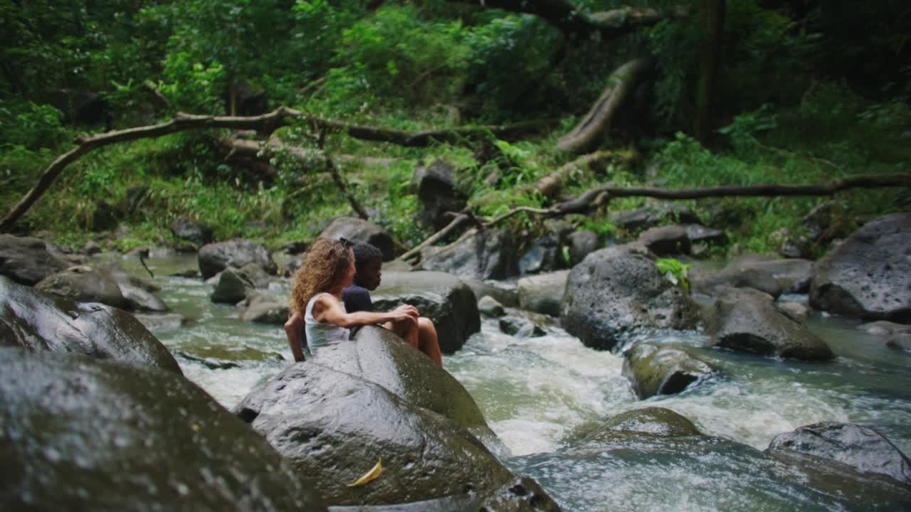 SLO MO.母子坐在瀑布底部视频素材