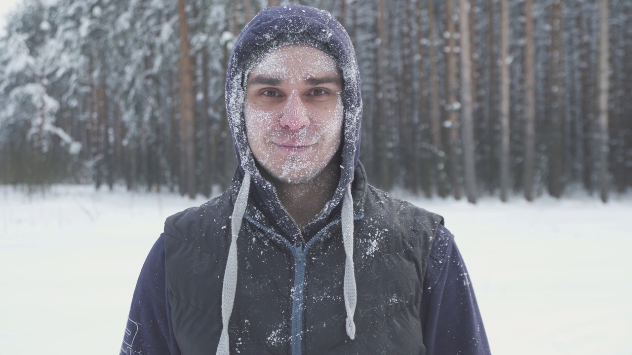 冬天的森林里，一个冰封的戴眼镜的男人，在一场暴风雪后，满脸积雪的他微笑着看着镜头视频素材