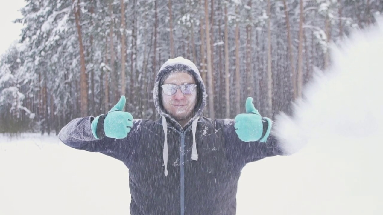 一个冻僵的人摆姿势在冬天的森林在下雪微笑视频素材