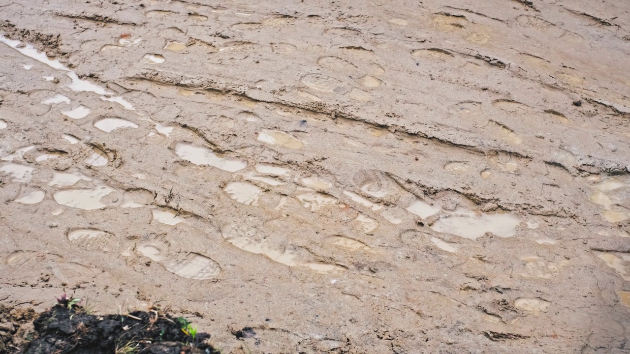 在潮湿泥泞的地面道路上被困在鞋印中的雨水水坑视频素材