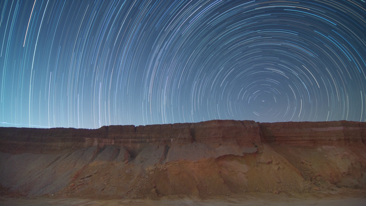 4K延时视频运动的夜空与圆形星星的轨迹在岩石形成山脉前景。湄莫，南邦，泰国。视频素材