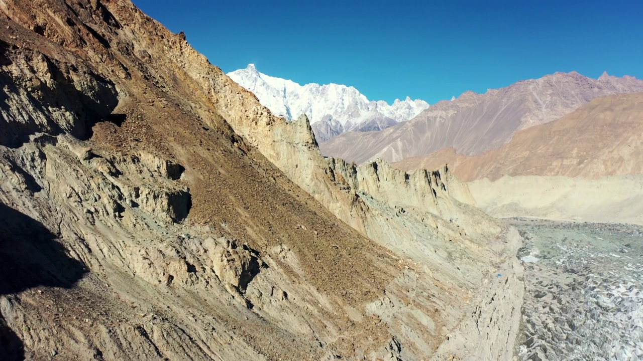 在巴基斯坦的罕萨山谷，飞机在被陡峭的雪山包围的宽阔冰川上移动视频素材