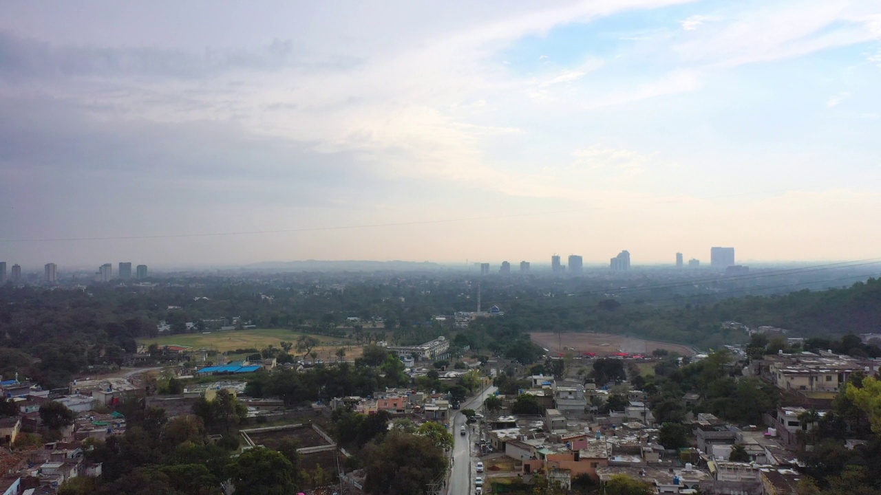 在一个朦胧的早晨，在远处高楼林立的城市上空升起的空中-巴基斯坦伊斯兰堡视频素材