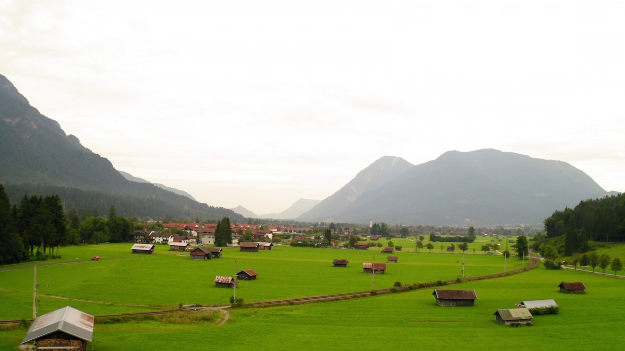 空中向前拍摄群山环绕的绿色景观上的住宅-德国Garmisch-Partenkirchen视频素材