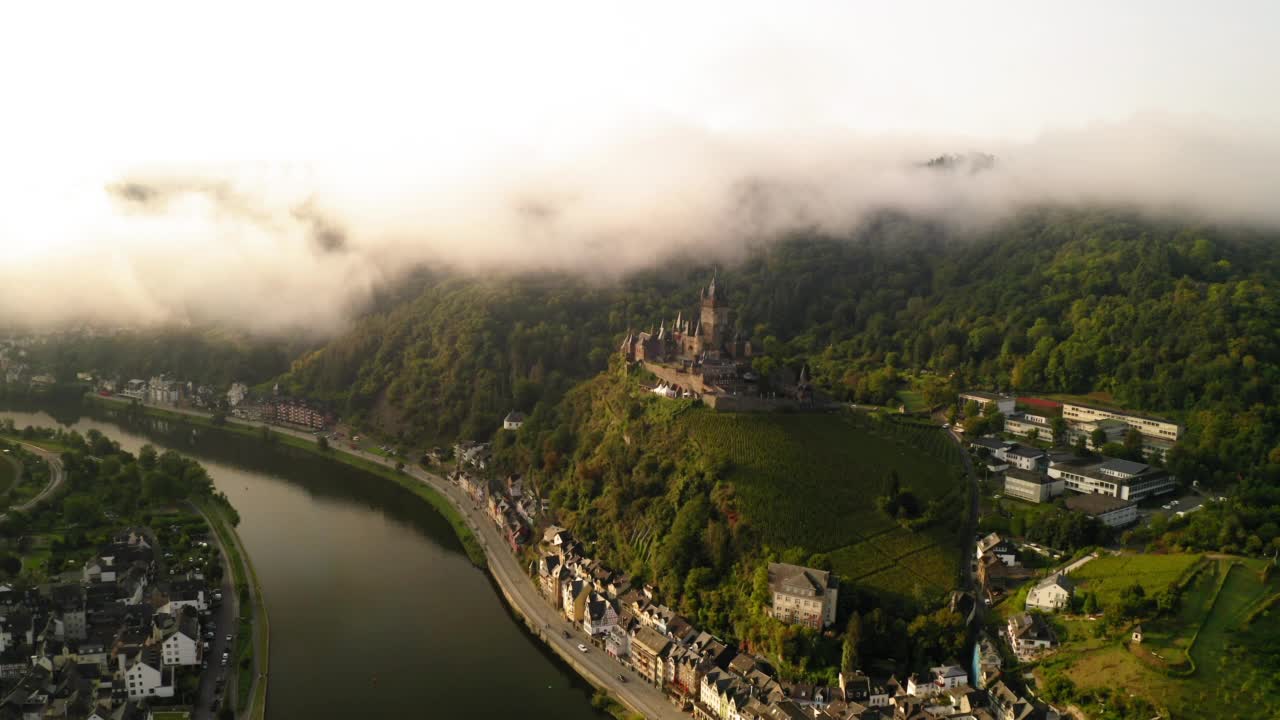 航拍11世纪的山顶城堡在城镇，无人机飞在河上在雾天- Cochem，德国视频素材