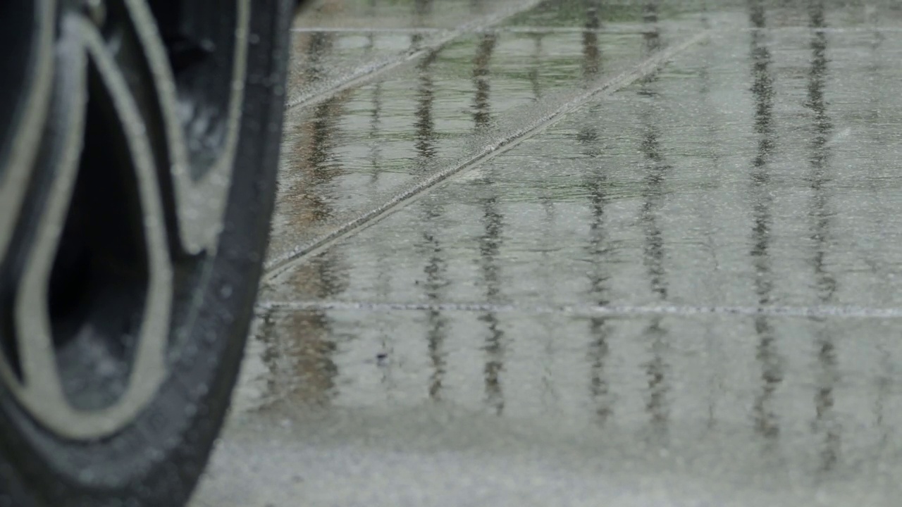 雨水飞溅，汽车轮胎在雨水。在雨中停车。雨季和轮胎在潮湿的路面上。靠近汽车轮胎或车轮在潮湿的道路上。代表汽车在雨季的概念。视频素材