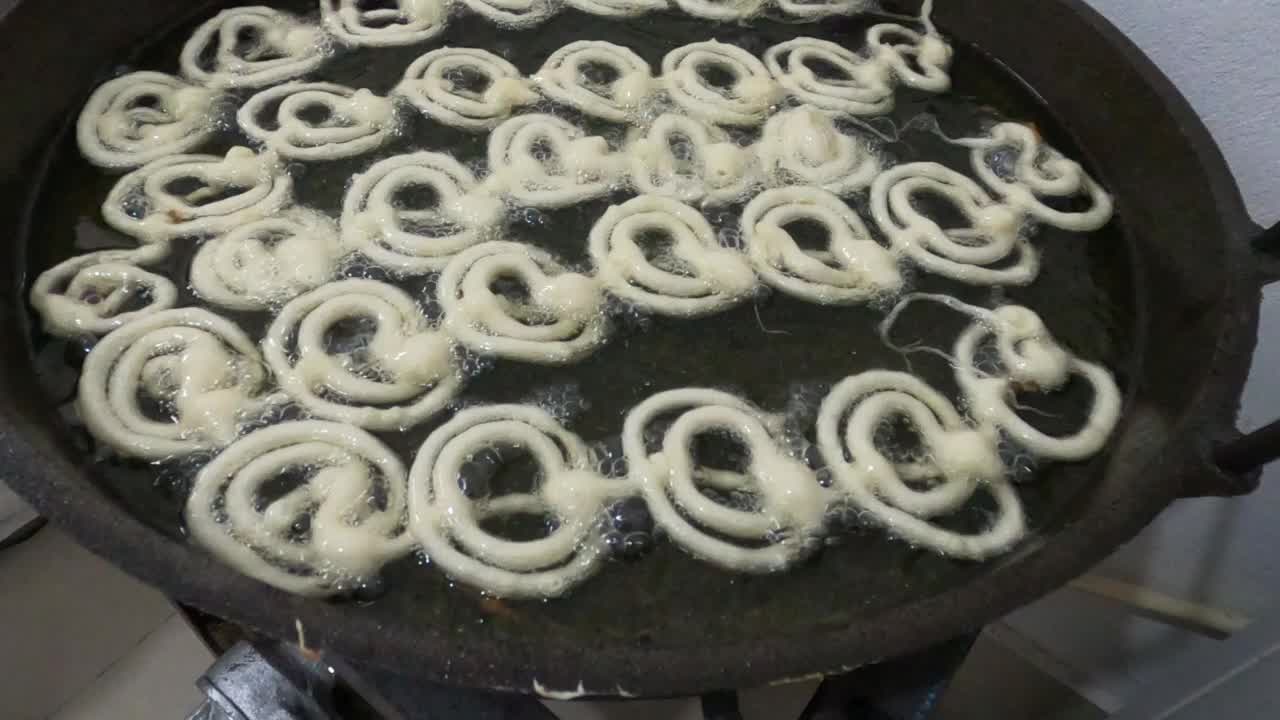 生吉拉皮油炸4k视频剪辑。用热锅做吉拉皮。Jalebi，也被称为jilapi, jilebi, jilipi, zulbia, jerry, mushabak，或zalabia，是一种受欢迎的印度甜点。视频素材