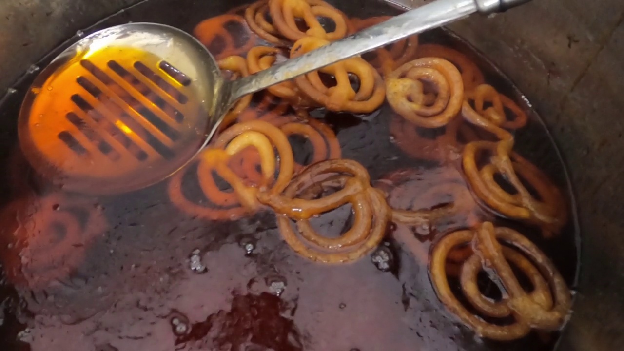 生吉拉皮油炸4k视频剪辑。用热锅做吉拉皮。Jalebi，也被称为jilapi, jilebi, jilipi, zulbia, jerry, mushabak，或zalabia，是一种受欢迎的印度甜点。视频素材