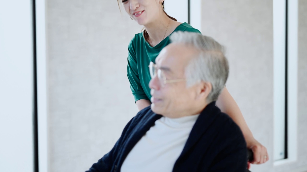 在养老院，年轻女子推着轮椅上的残疾老年男子。视频素材