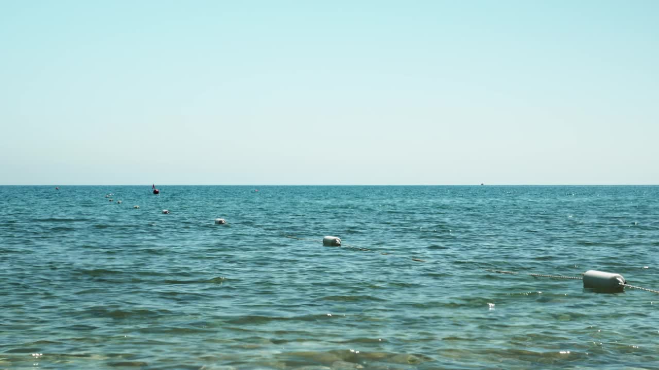 围起来的浮标漂浮在海上的波浪上。宁静的海景，海面清澈，卵石底部有浮标。夏日里，透明的水波荡漾。夏天海滩度假视频素材