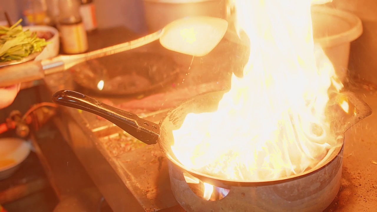 厨师在厨房用炒锅里的火炒中国牵牛花，这是泰国很受欢迎的街头小吃视频素材