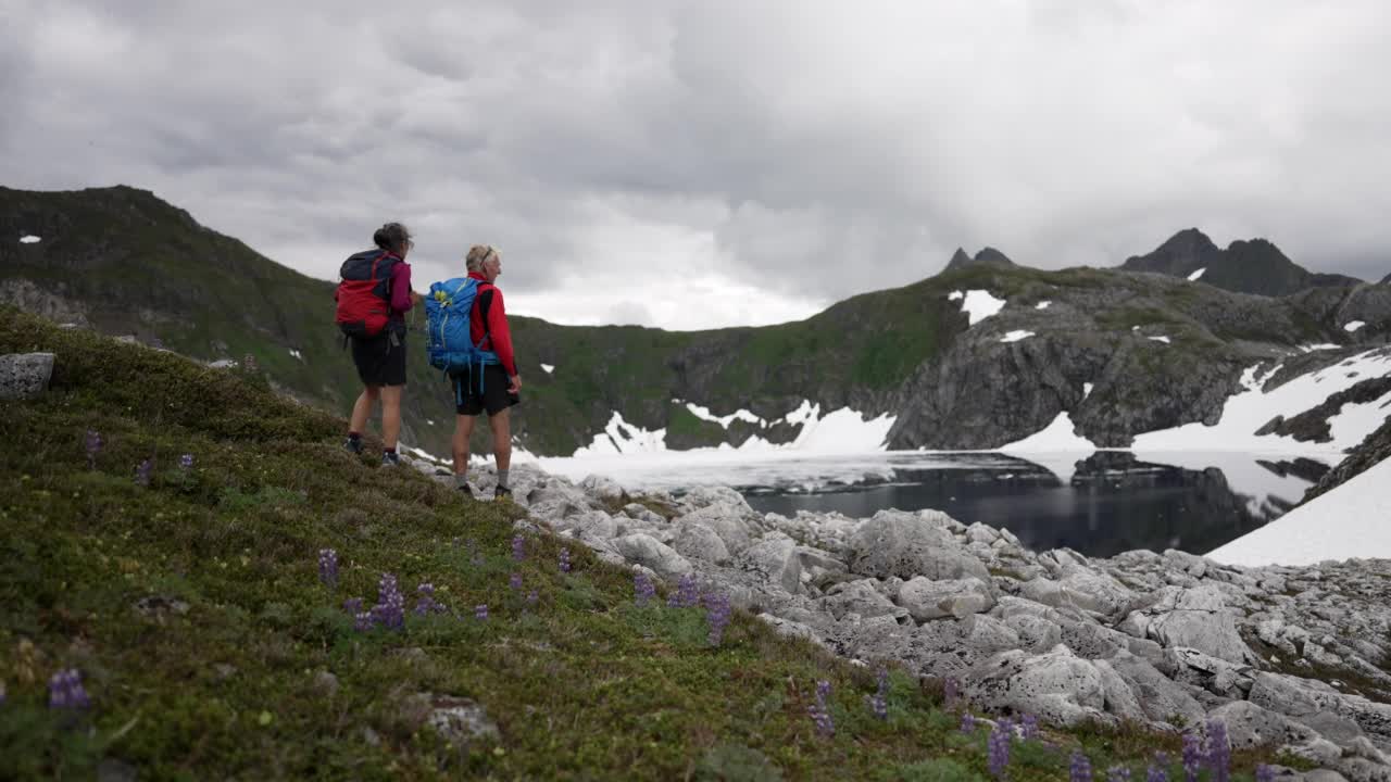 一对上了年纪的徒步旅行者在一个阴天的湖边视频素材