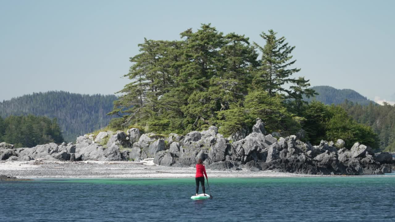 一个女人站在有山的海湾里划船视频素材