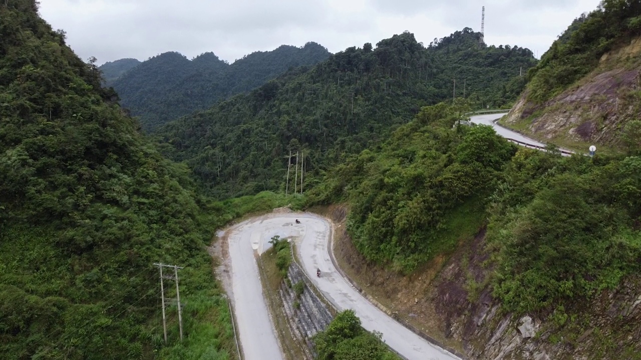 山间弯弯曲曲的公路鸟瞰图，环绕着绿色的森林视频素材