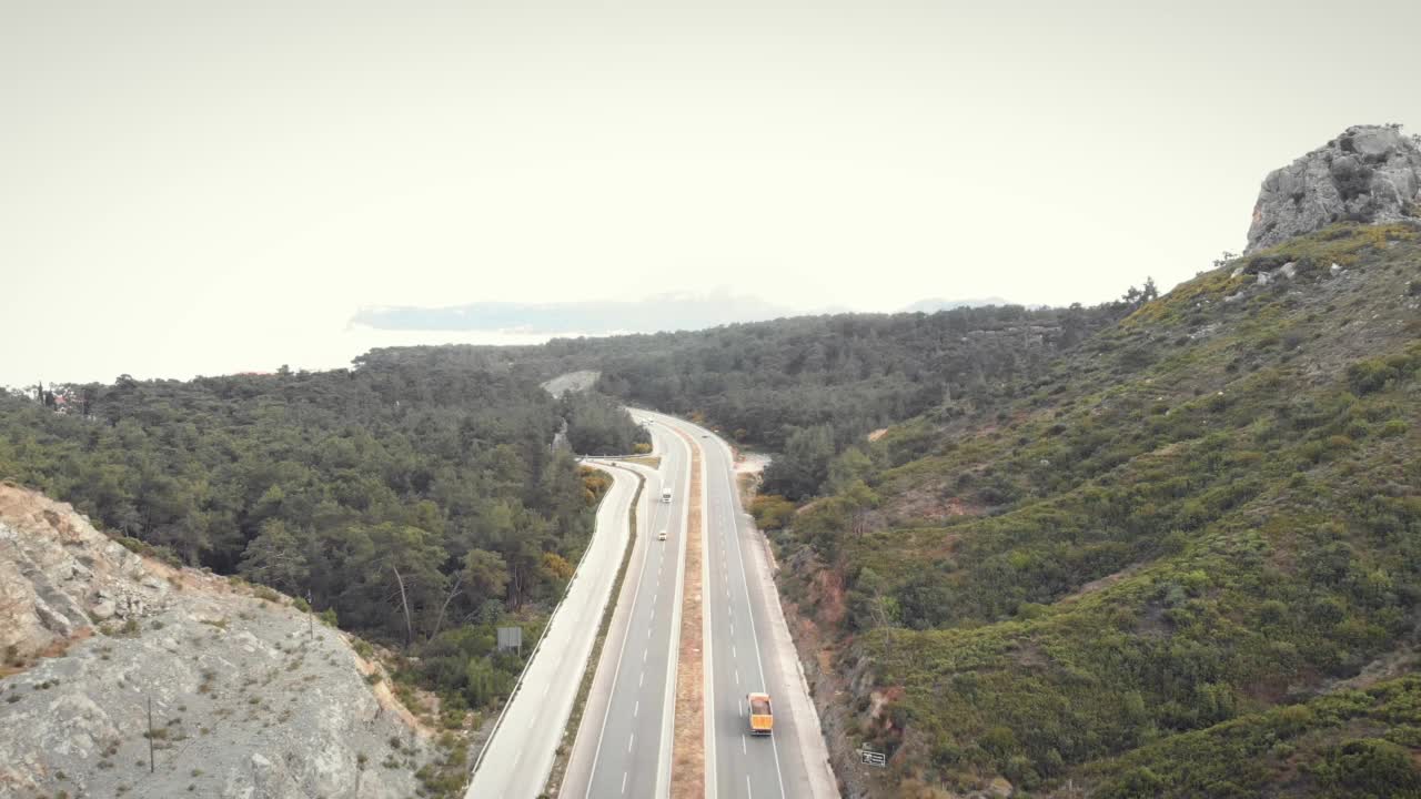 现代高速公路穿过山脉沿着美丽的海岸线。汽车、公共汽车和卡车沿着美丽的海岸线在高速公路上快速行驶。繁忙的高速公路上挤满了游客、巴士和汽车视频素材