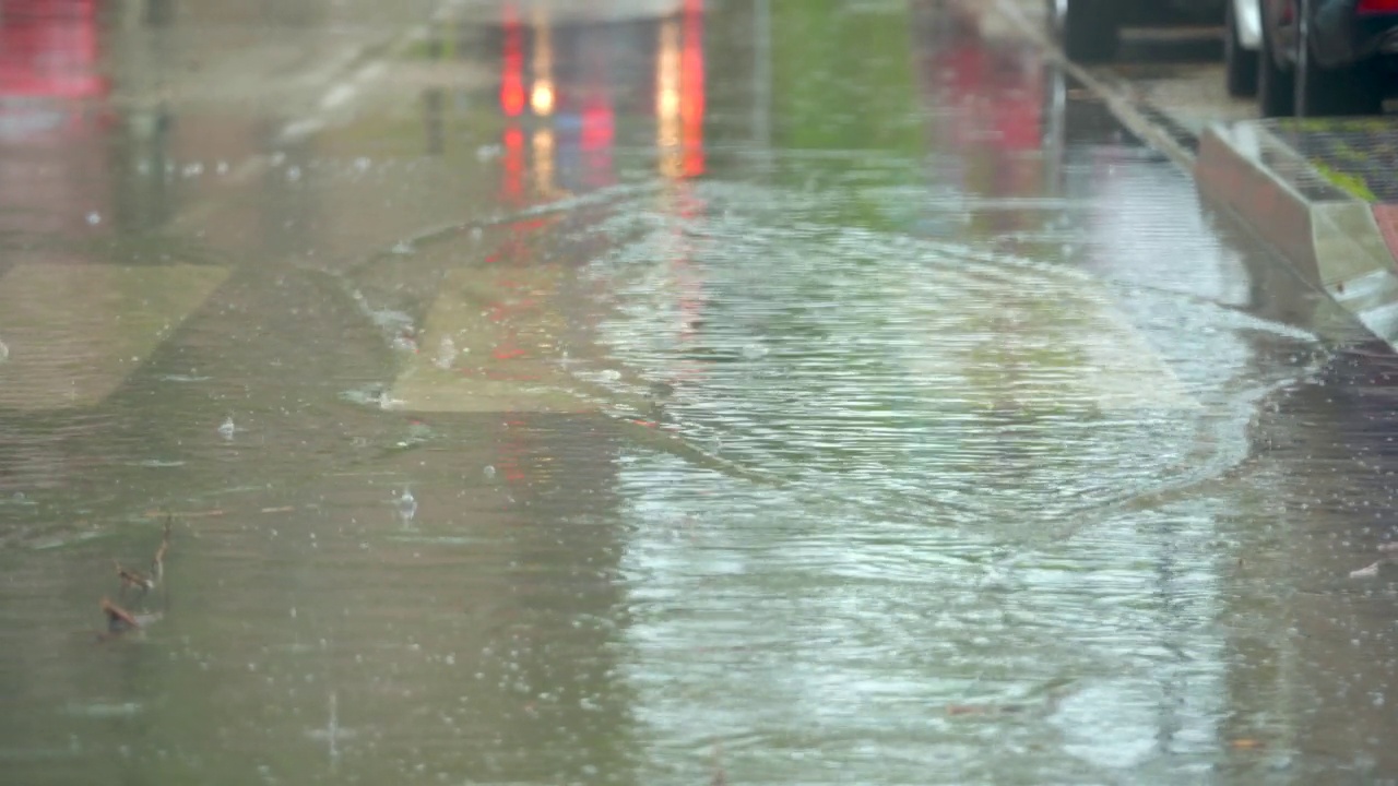 汽车穿过街道，溅起了雨水形成的大水坑视频素材