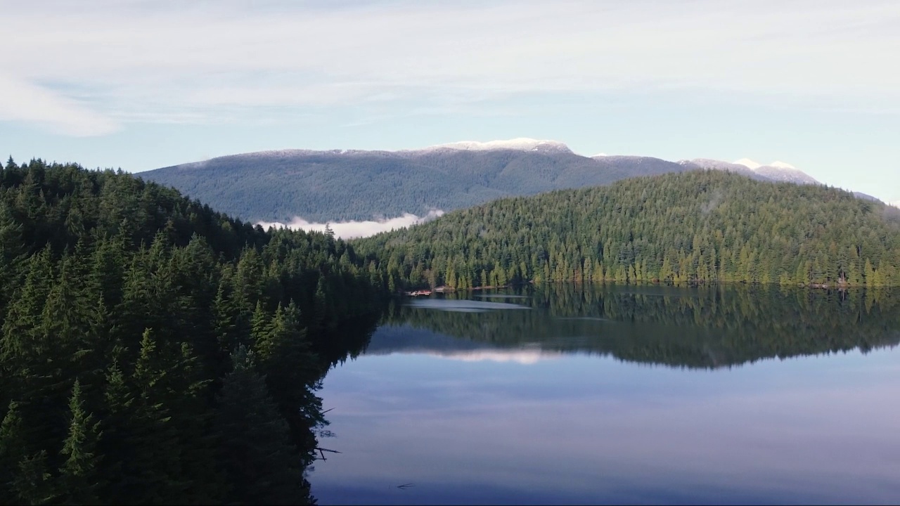 清澈的湖全景，山上覆盖着绿色的松树视频素材