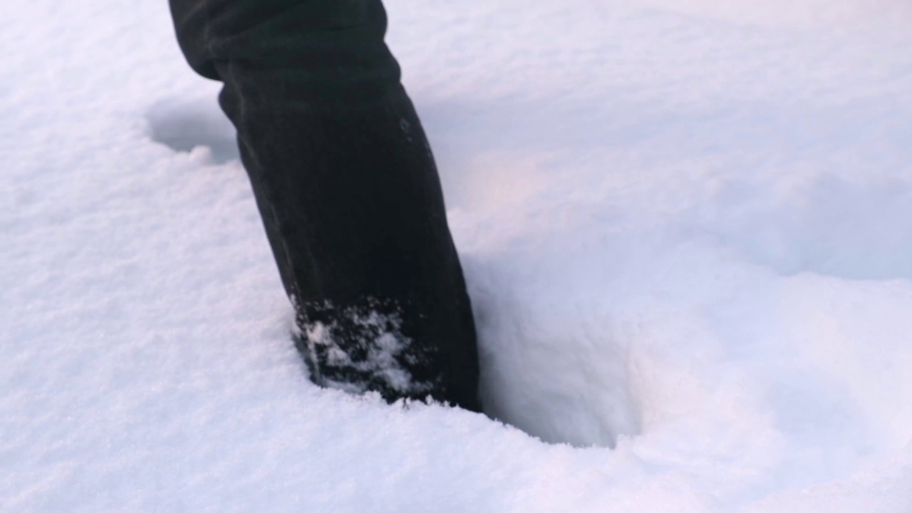 一个穿靴子的人走过雪堆。视频素材