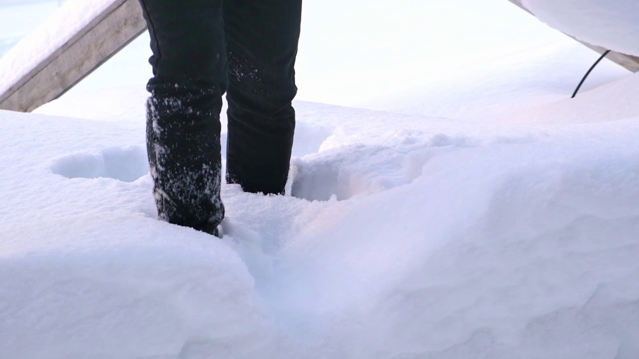 一个穿靴子的人走过雪堆。视频素材