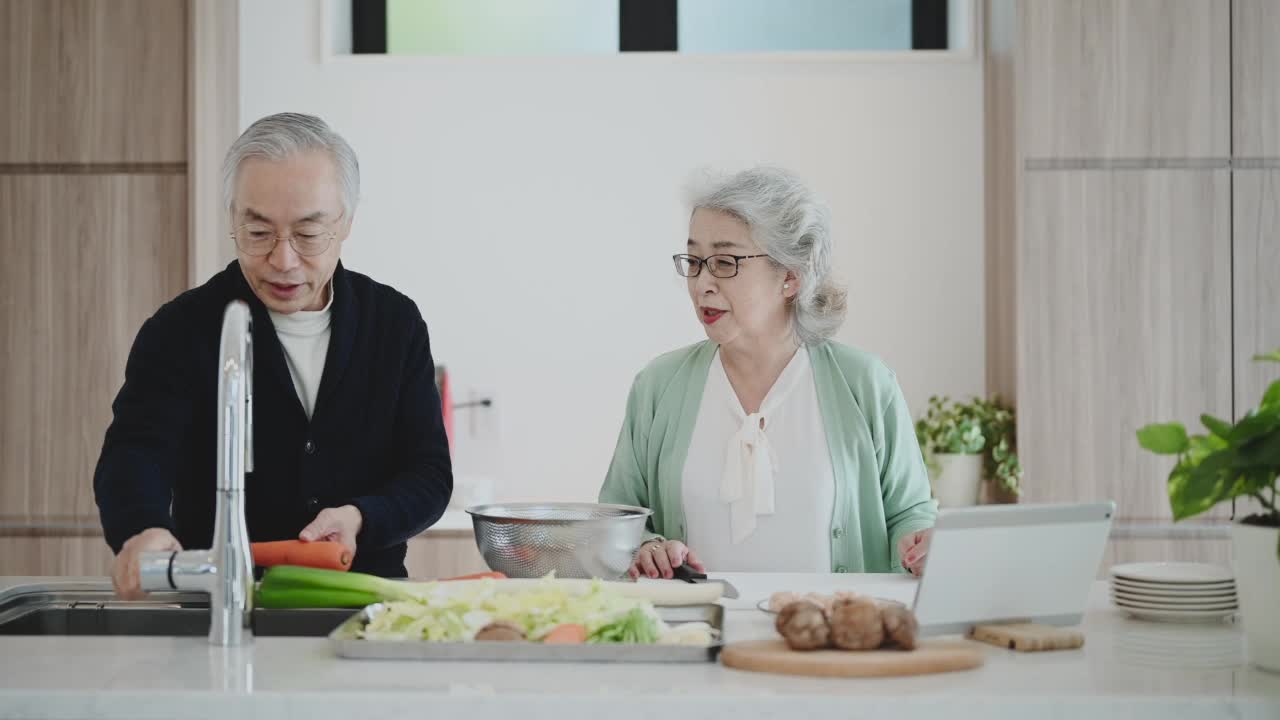 老夫妇带着平板电脑，一起在家做饭。视频素材