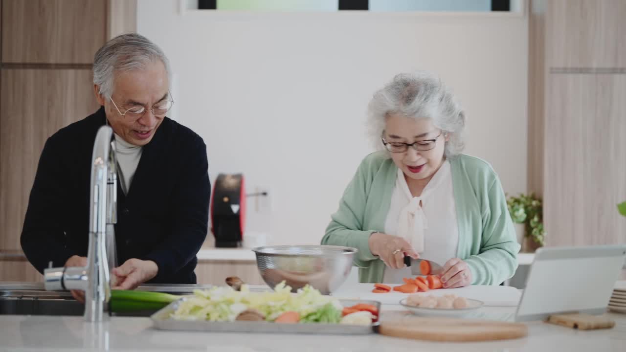 老夫妇带着平板电脑，一起在家做饭。视频素材