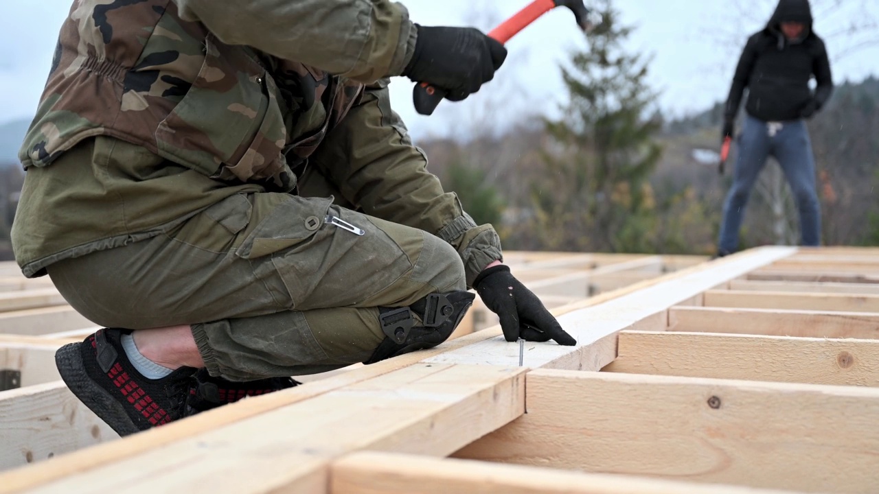 男子工人在建造木制框架房屋时敲击。视频素材