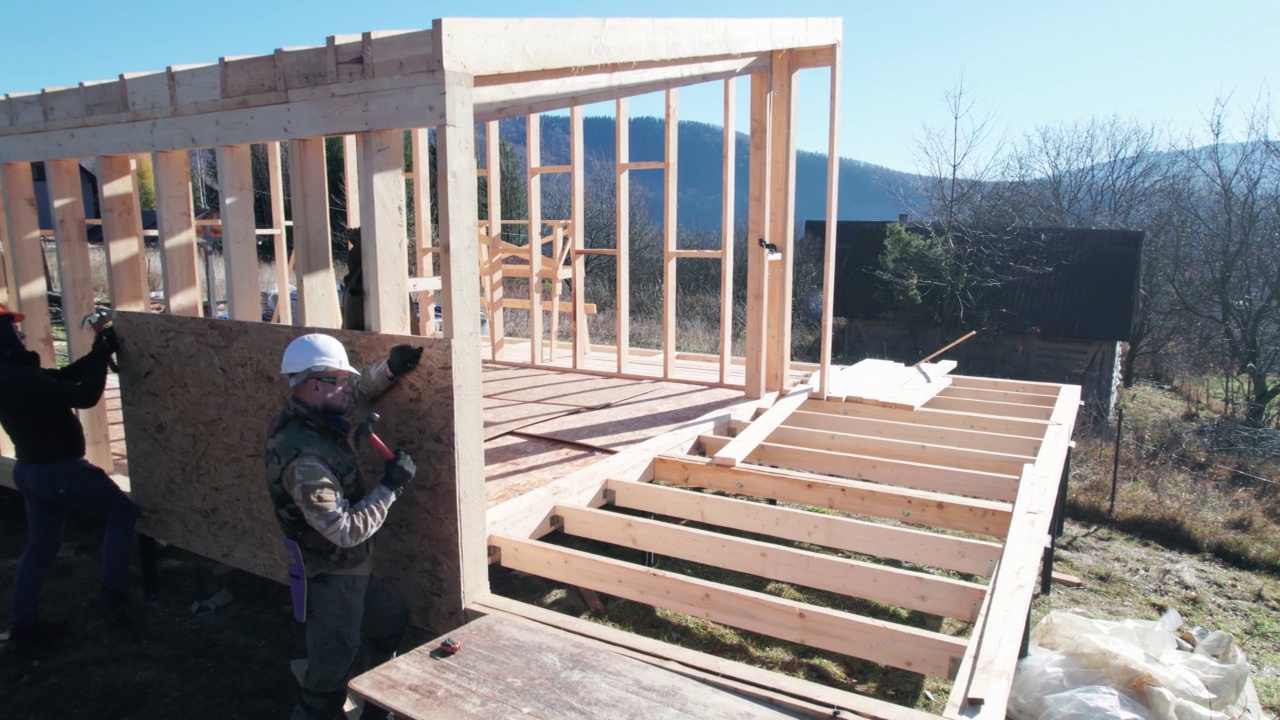 木匠在建造木结构房屋时将钉子钉入OSB面板。视频素材