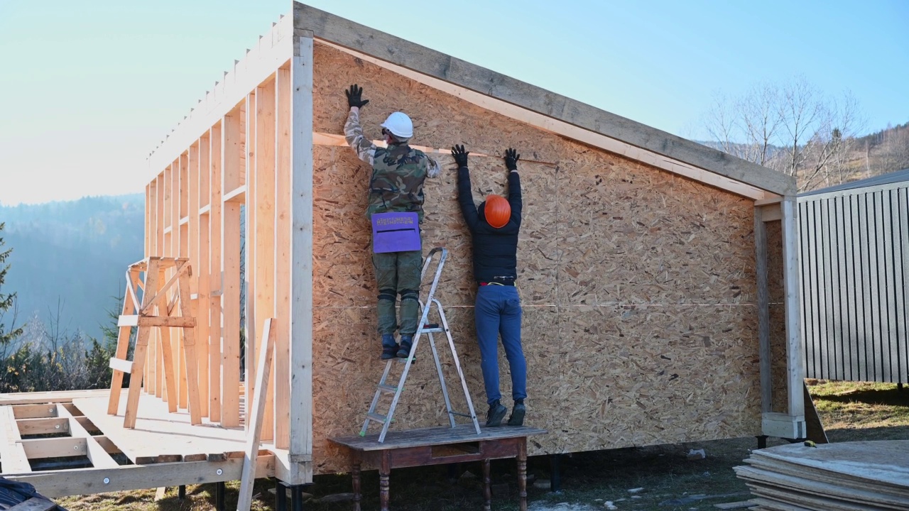 工人正在建造木制框架房屋，安装木质OSB板。视频素材