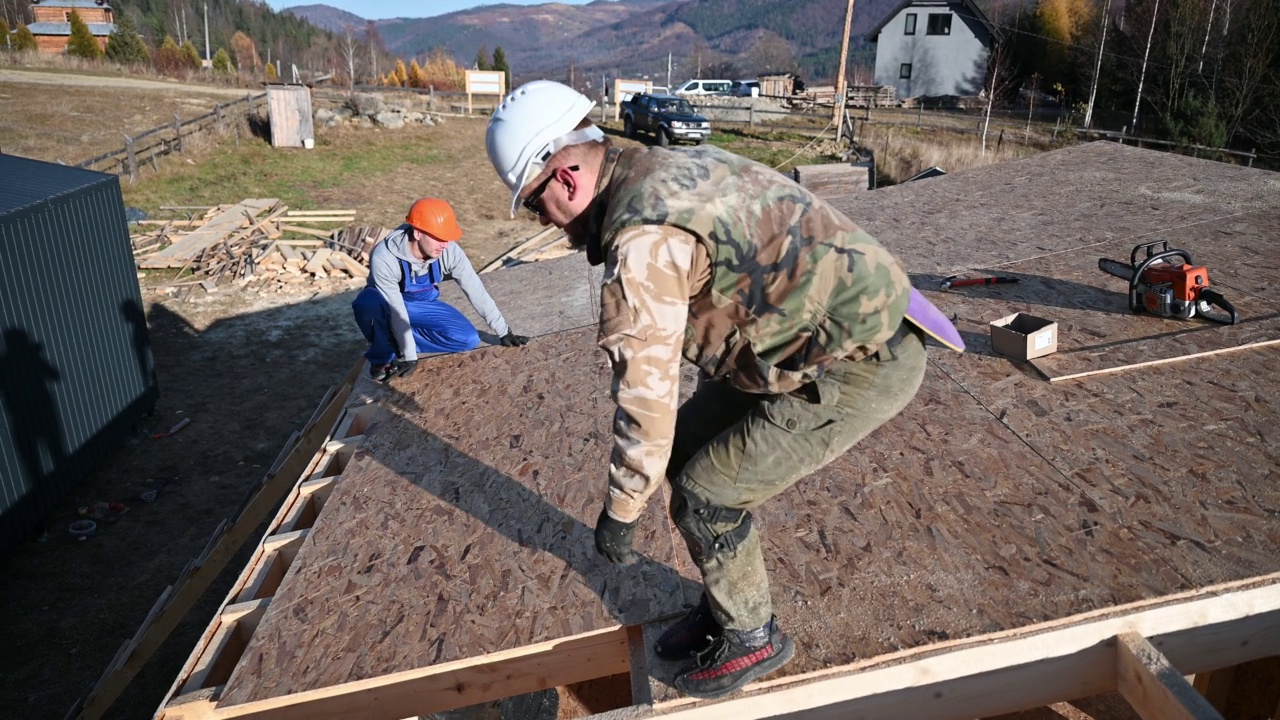 工人正在建造木制框架房屋，安装木质OSB板。视频素材