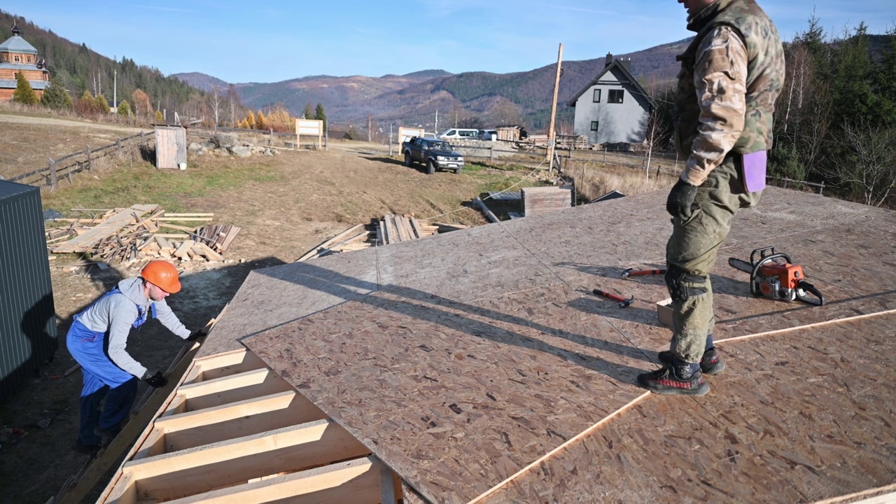 工人正在建造木制框架房屋，安装木质OSB板。视频素材