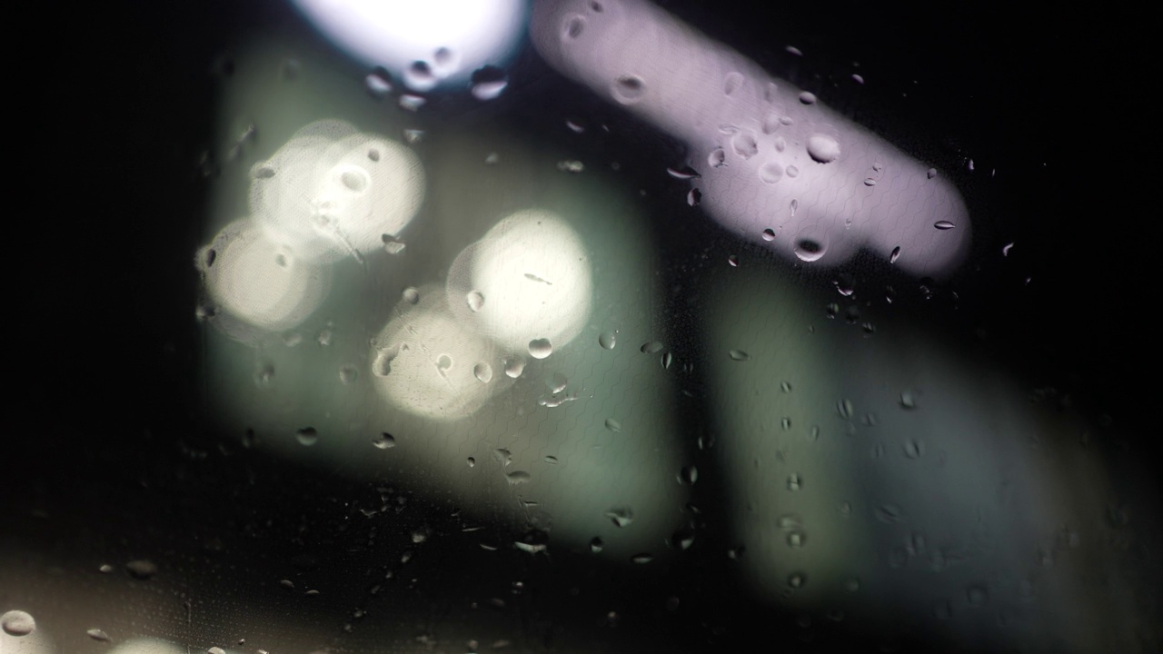 玻璃上的水滴，雨。雨天，大雨落在窗户上夏天阵雨时，大雨滴打在窗玻璃上。背景上的平光源。抽象的散景视频素材