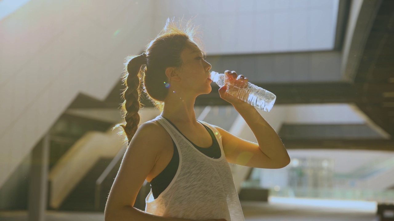 年轻女子在运动后喝水视频素材