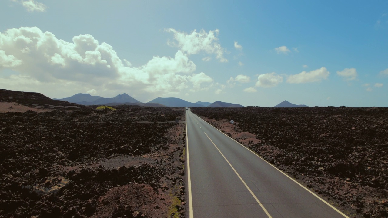 无人机拍摄的空旷道路沿着蒂曼法亚国家公园的岩石火山自然景观。加那利群岛，兰萨罗特，西班牙。没有人视频素材