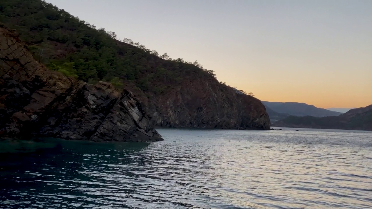 海边的落日，水面上的波浪，地平线上的卡特尔和岛屿的剪影视频素材