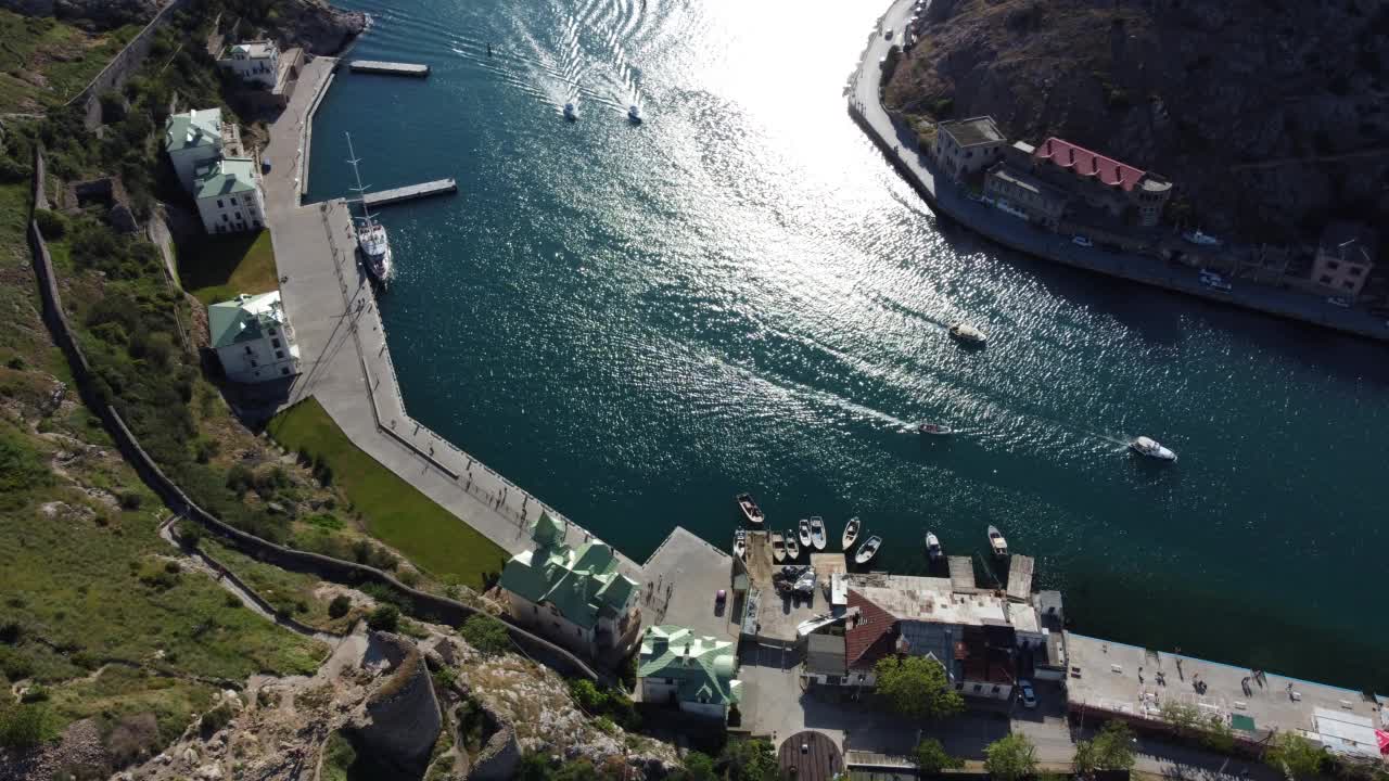 在阳光明媚的日子里，航拍巴拉克拉瓦岛景观的全景，滨海湾的船只和大海。克里米亚塞瓦斯托波尔旅游景点。无人机俯视拍摄港口的豪华游艇，船只和帆船视频素材