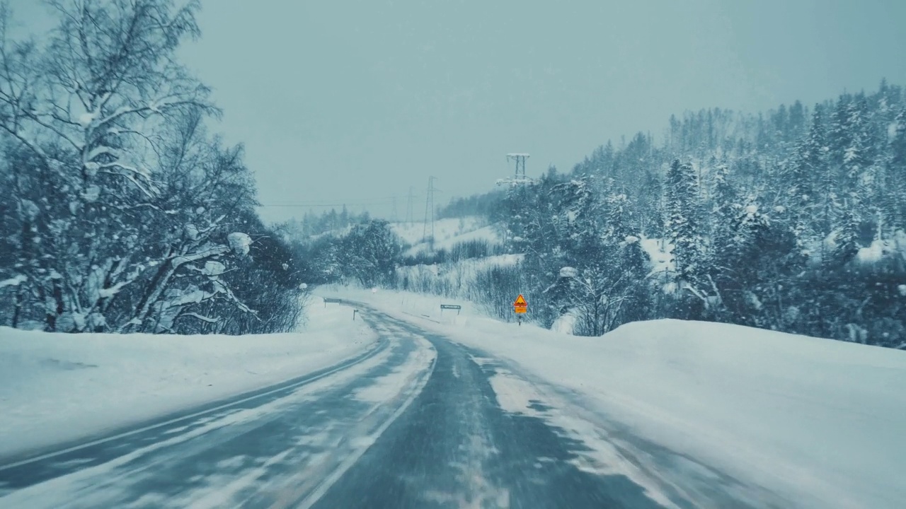 一辆汽车在暴风雪中行驶在高速公路上。透过汽车挡风玻璃看。视频素材