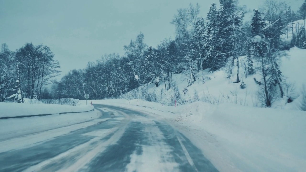 一辆汽车在暴风雪中行驶在高速公路上。透过汽车挡风玻璃看。视频素材