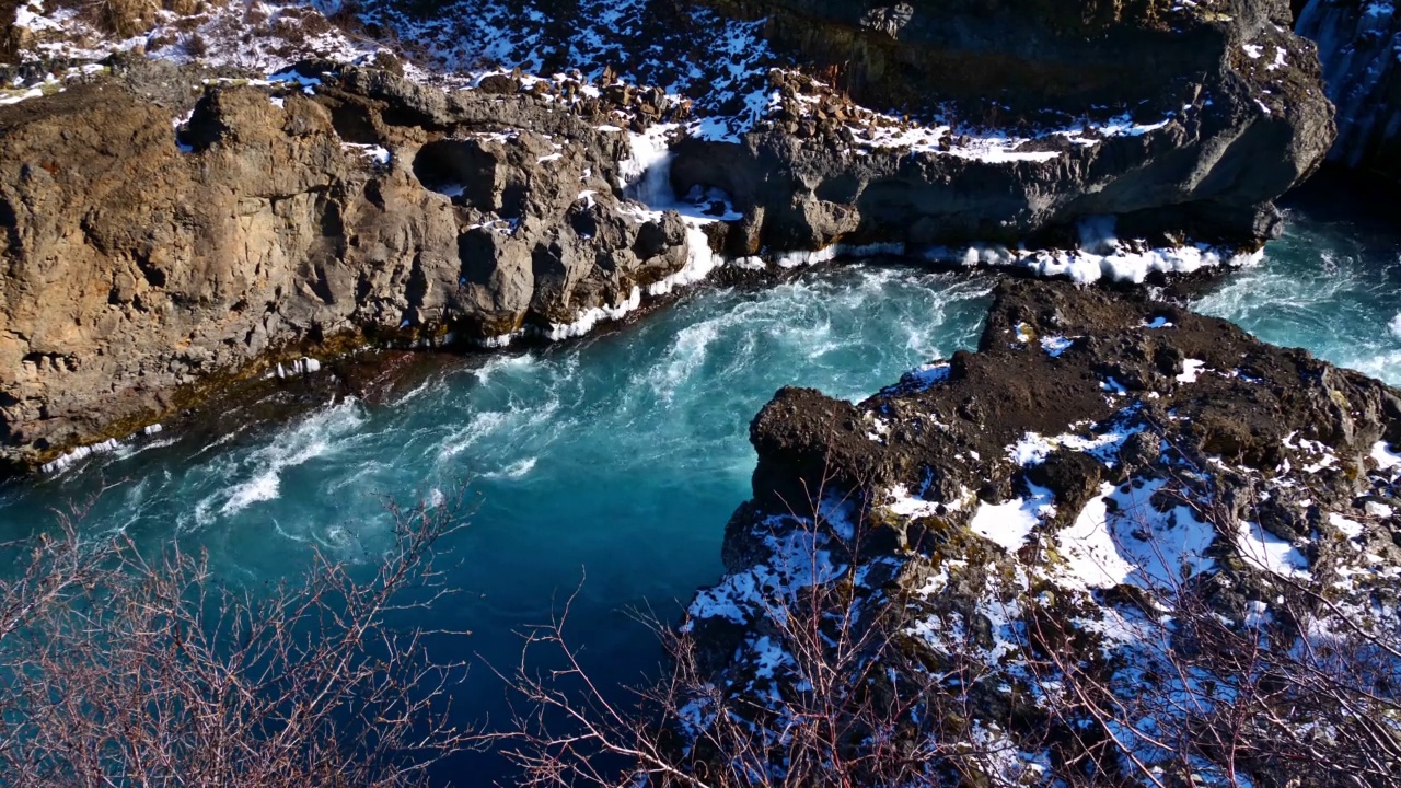 在冰岛西部Húsafell，阳光明媚的冬日里，河水呈蓝绿色，这是Hraunfossar瀑布附近汹涌的河流的高角度视图。视频素材